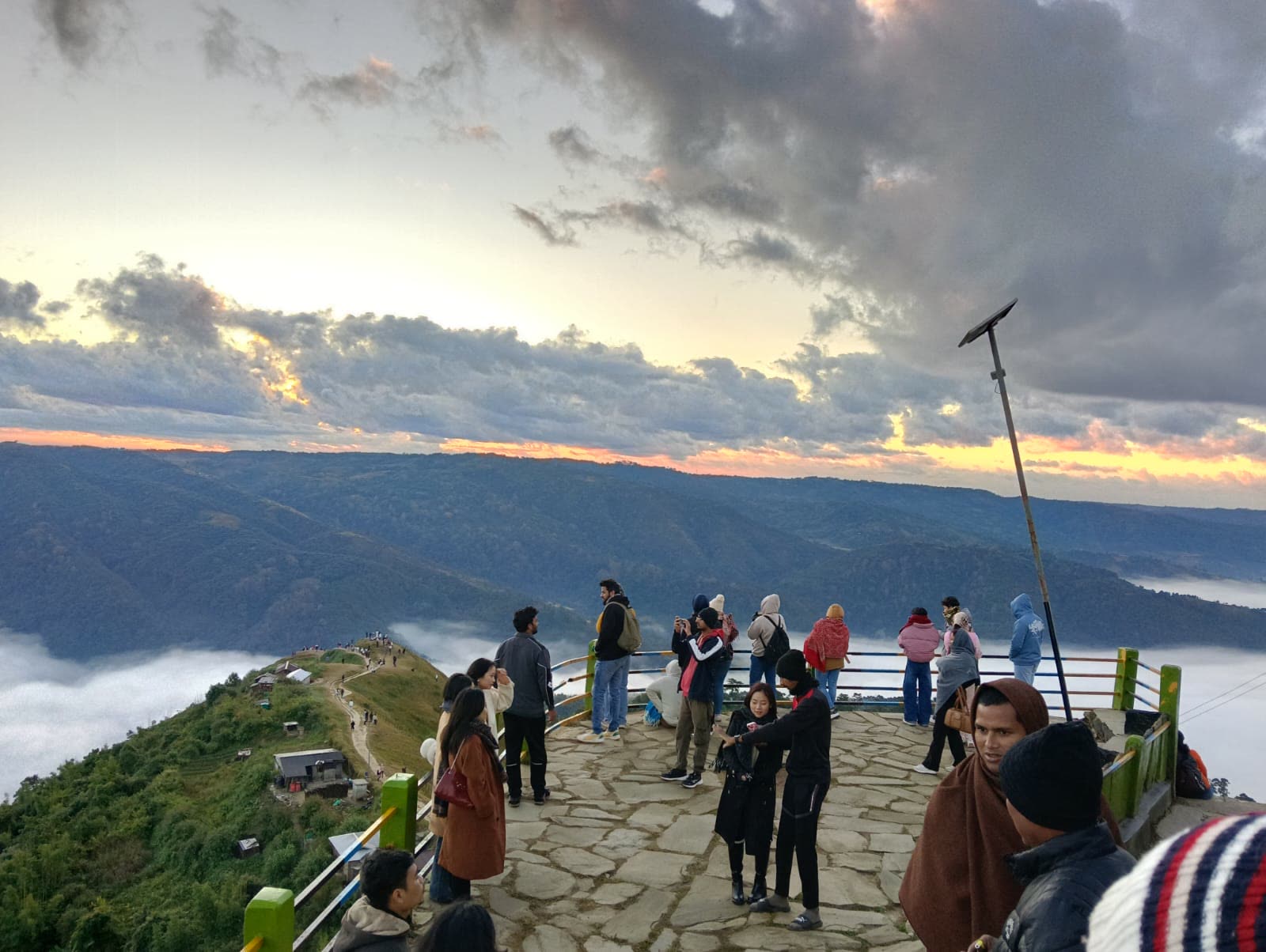 Travellers watching the sunset over cloud-filled valleys in Meghalaya